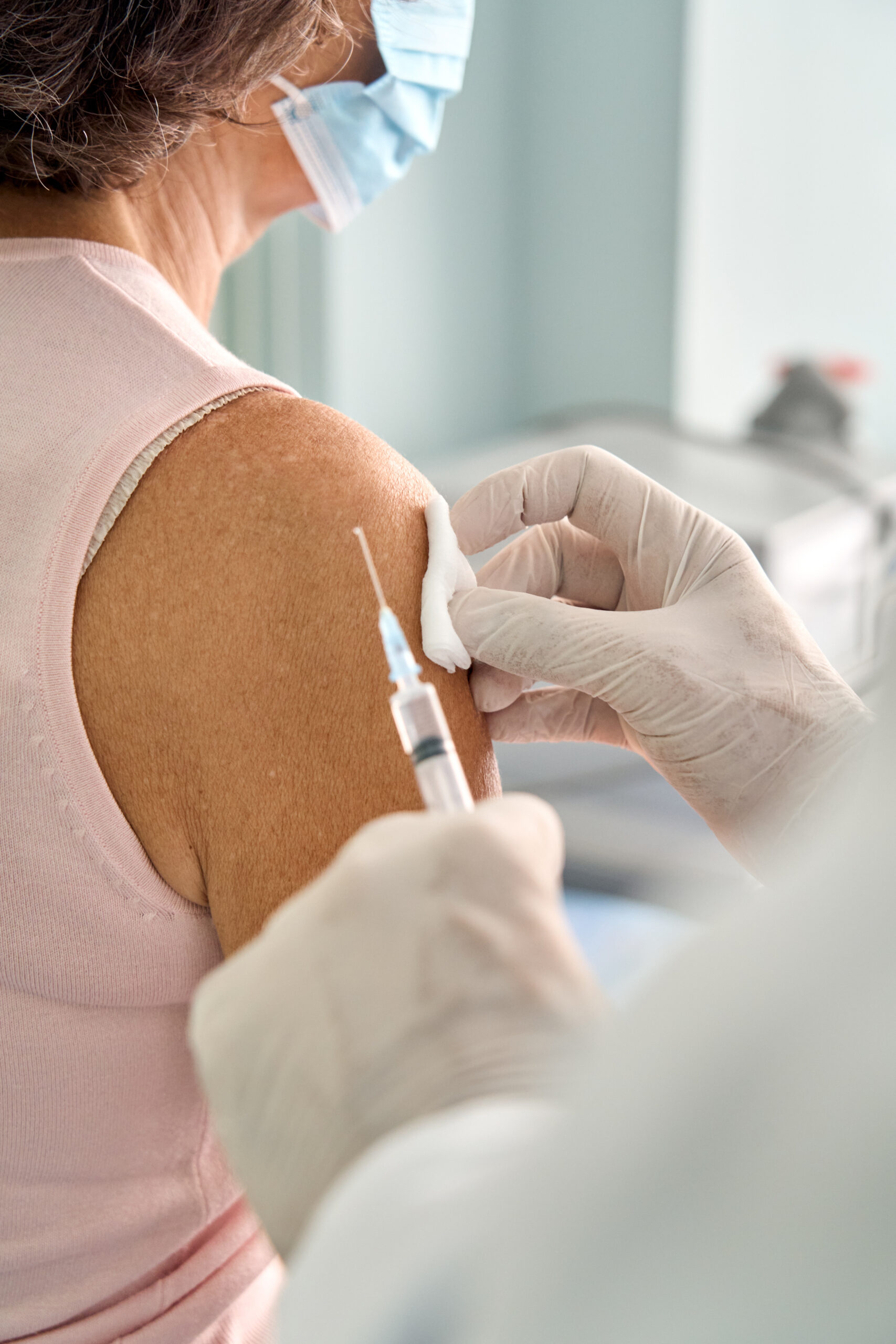 Older senior woman wearing face mask getting vaccination injection.